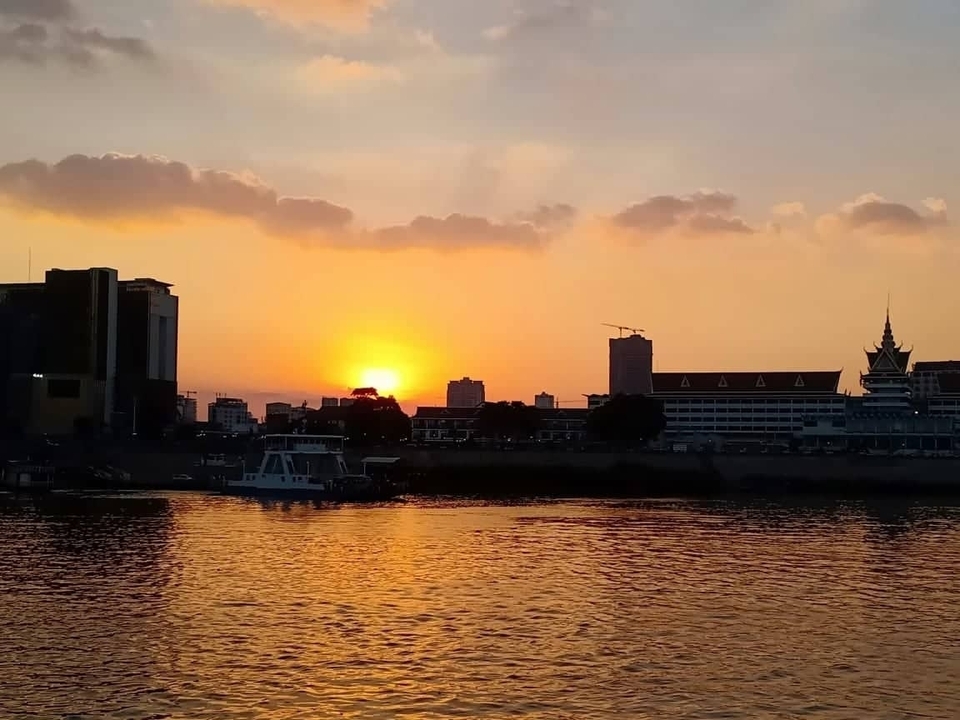 Coucher de soleil sur l'horizon urbain avec des bâtiments reflétant la lumière du soleil sur l'eau.