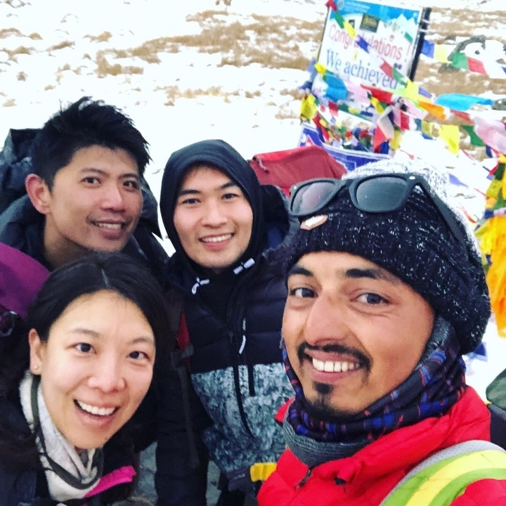 Groupe de randonneurs posant avec des drapeaux de prières colorés.