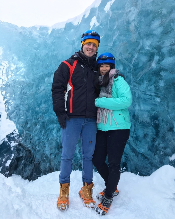 Two people standing in front of a wall of ice.