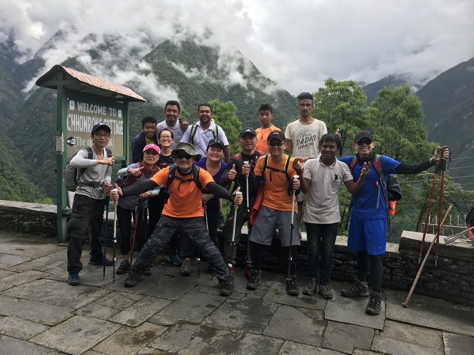 Un groupe de personnes posant à un départ de sentier dans une région montagneuse luxuriante.
