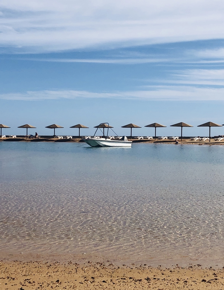 Bateau ancré le long d'un littoral avec des parasols en paille.