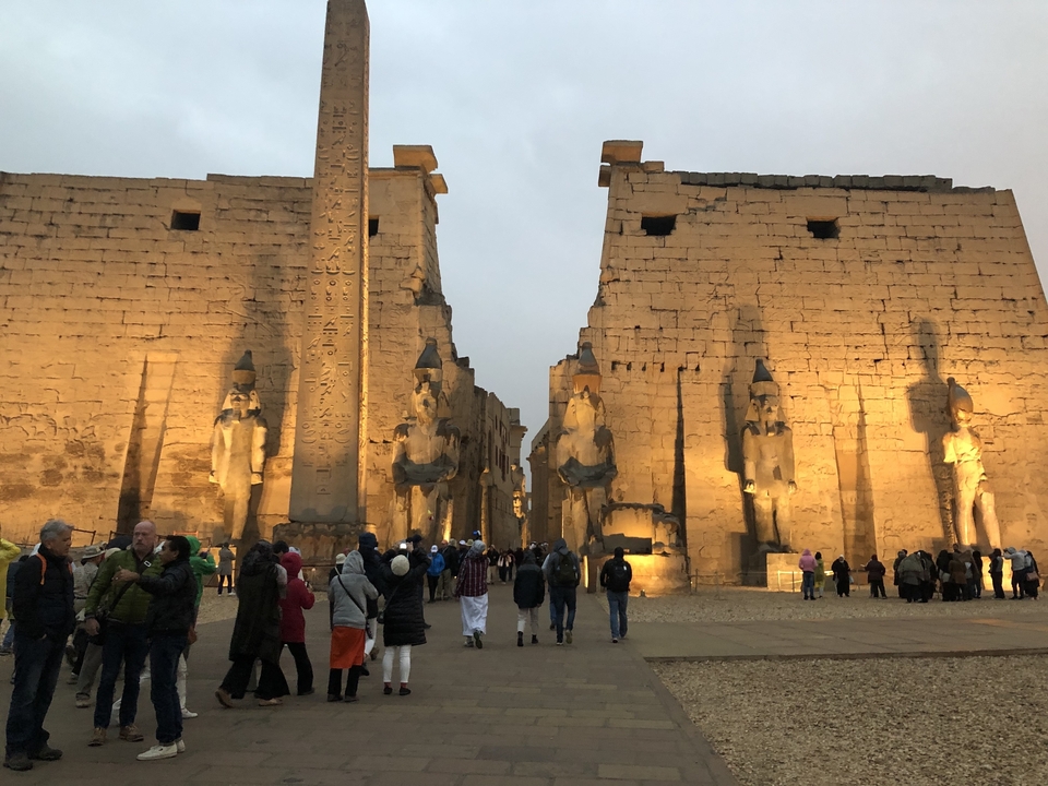Grand complexe de temples anciens illuminé la nuit avec de nombreux visiteurs.