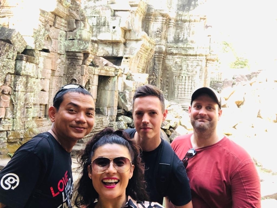 Four people posing in front of ancient temple ruins.