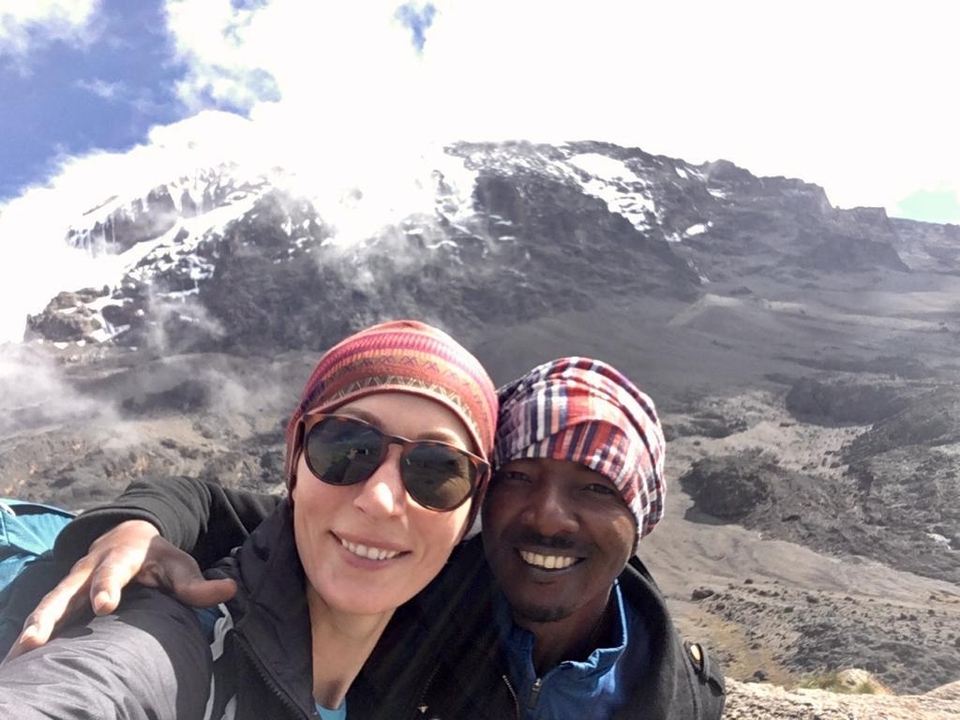 Deux personnes souriantes avec le mont Kilimandjaro en arrière-plan.