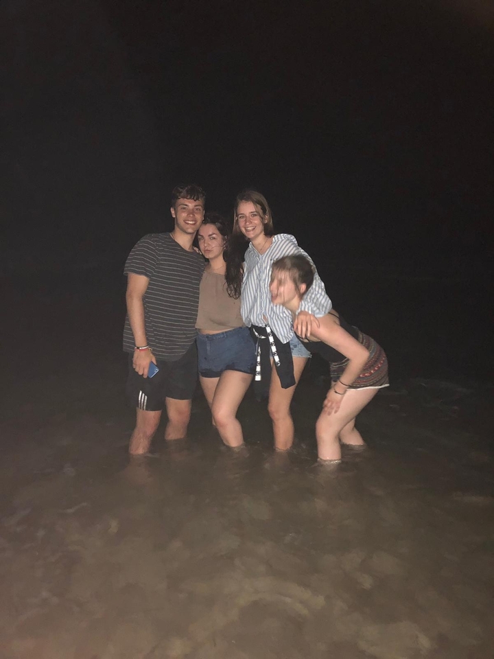 Quatre amis debout dans l'eau la nuit.