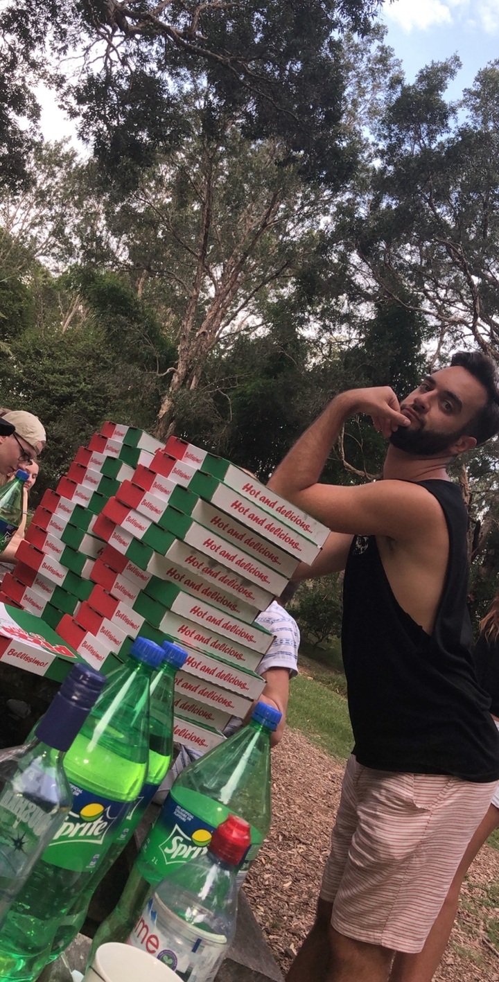 Personne qui pose avec humour avec des boîtes de pizza empilées à l'extérieur.