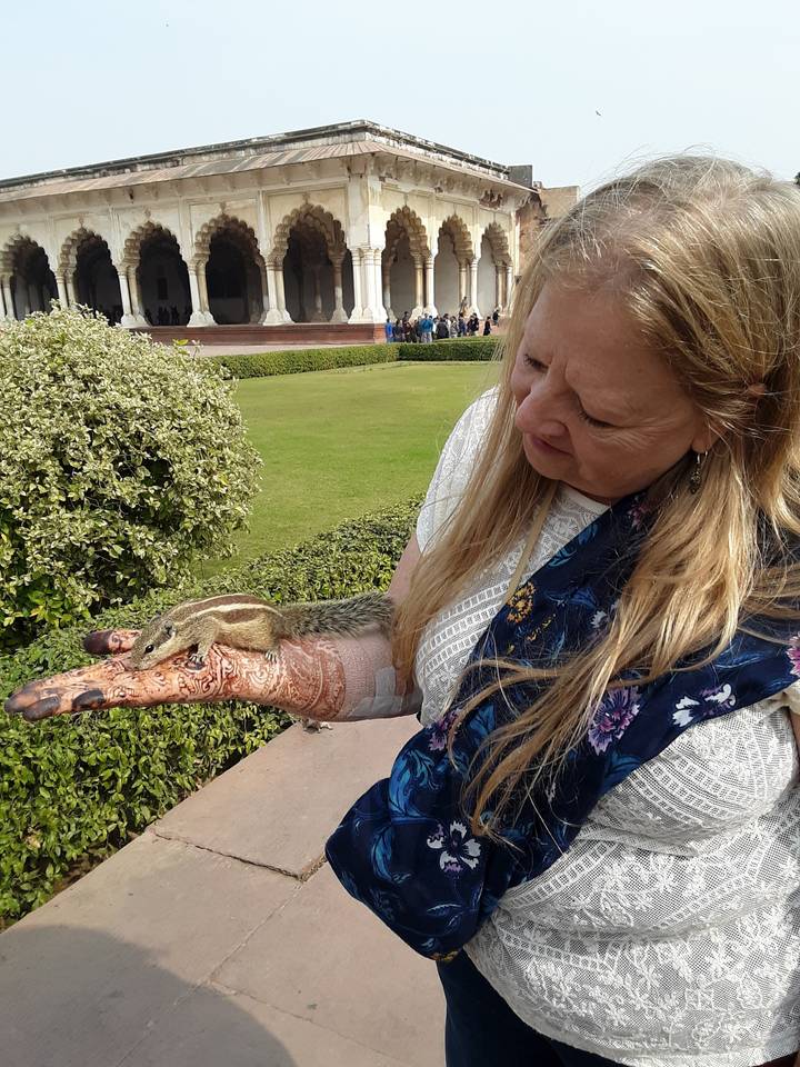 Une femme avec du henné sur la main tenant un petit animal.