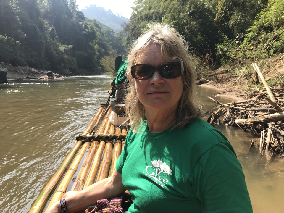 Une femme assise sur un radeau de bambou dans une rivière.