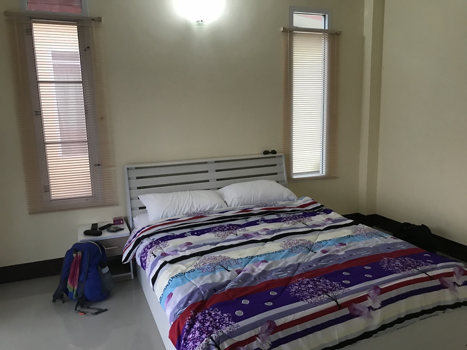 Une chambre d'hôtel simple avec un lit et des stores.