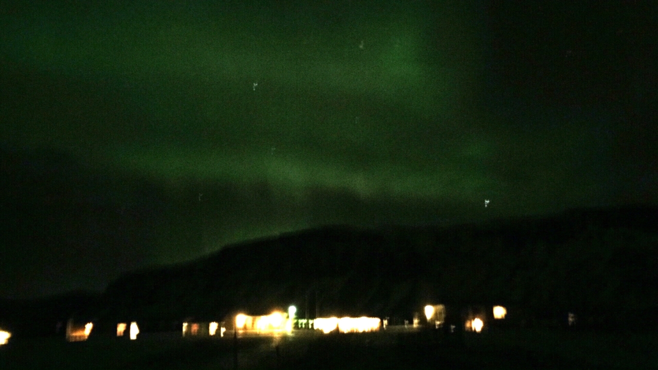 Vue floue des aurores boréales au-dessus d'un paysage lointain.