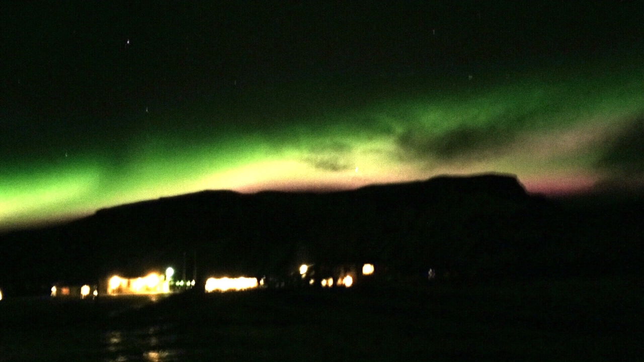 Vue floue des aurores boréales au-dessus d'un paysage sombre.