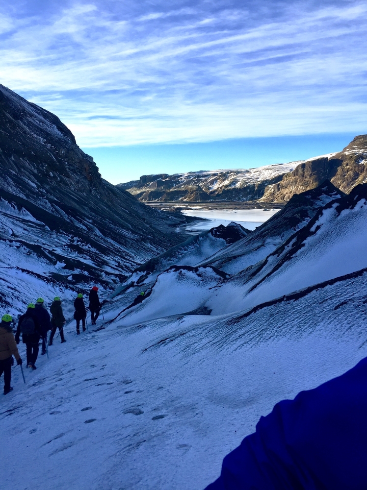 Des randonneurs marchant à travers une vallée enneigée.