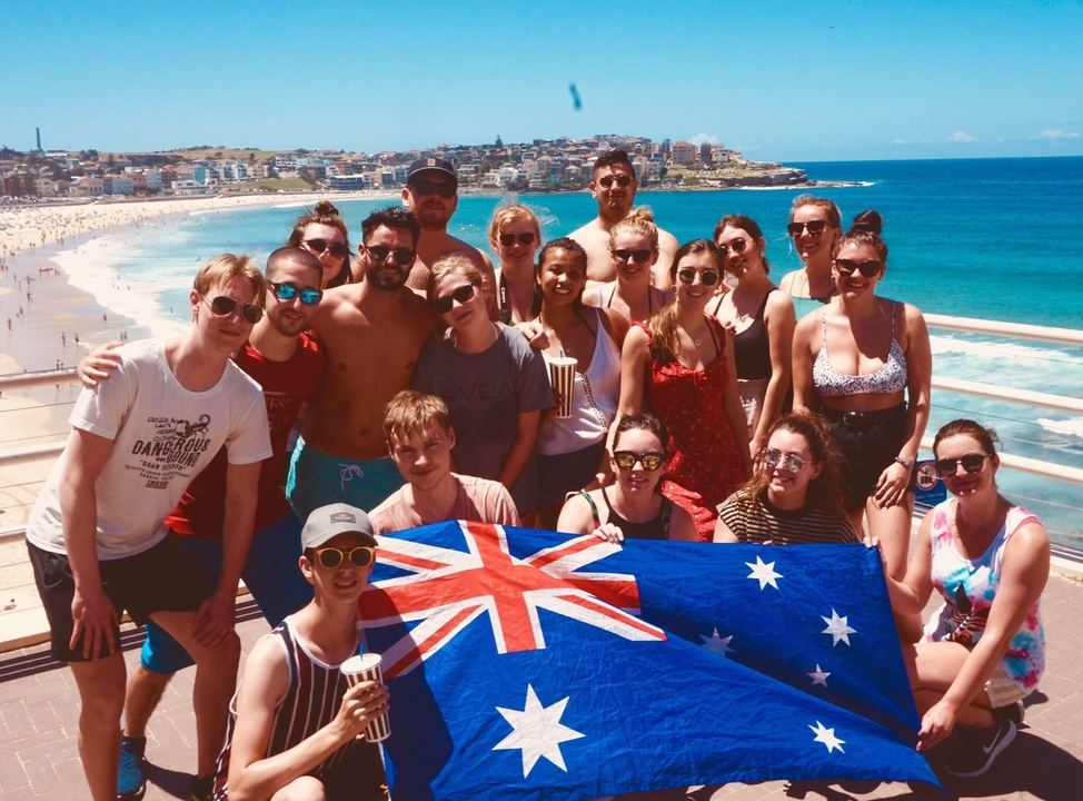 Group of people holding an Australian flag at the beach.