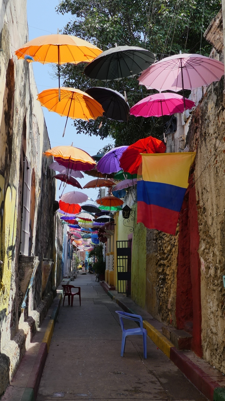Rue étroite décorée de parapluies colorés et d'un drapeau.