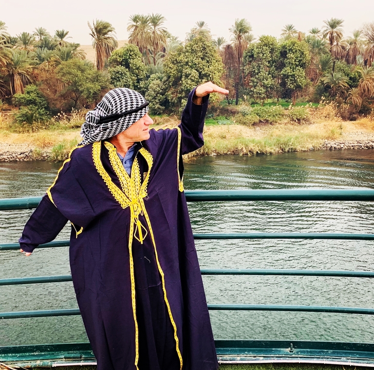 Homme en tenue traditionnelle posant près d'une rivière.