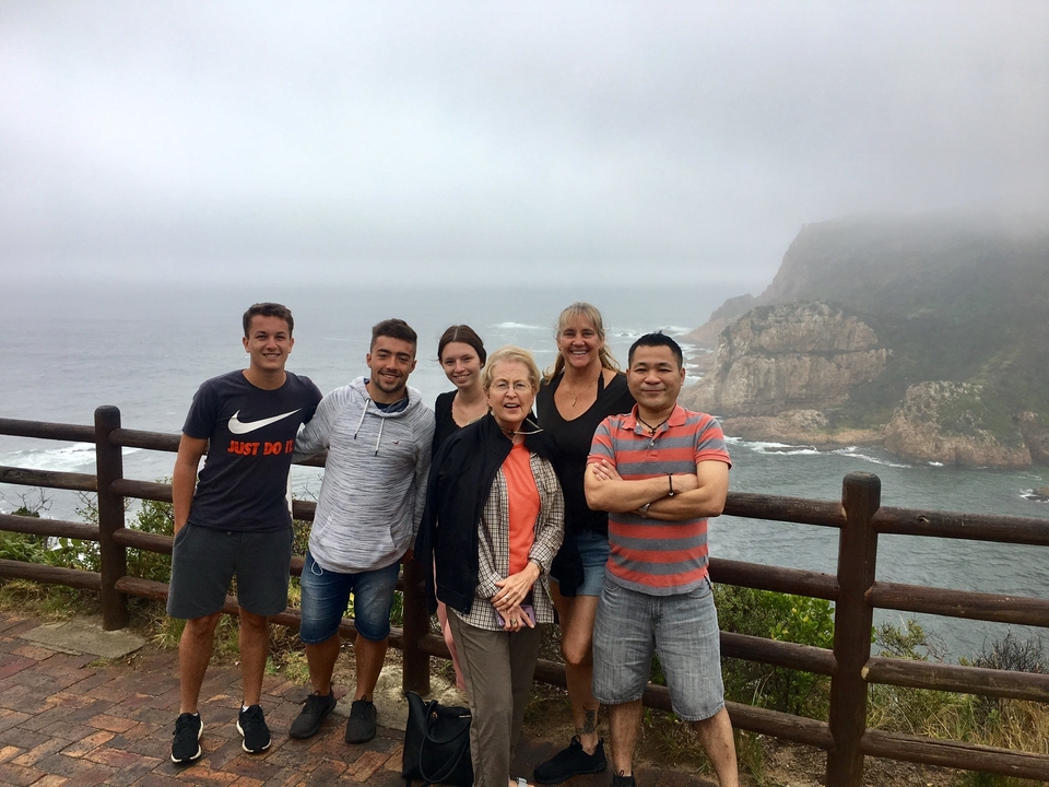 Groupe de personnes posant près de l'océan avec des falaises en arrière-plan.