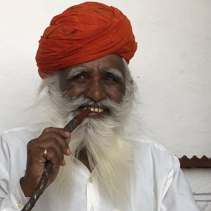 Gros plan d'un homme âgé souriant avec une pipe.