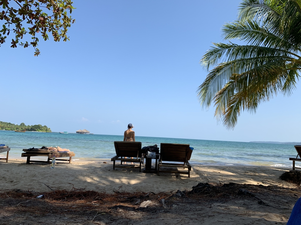 Personne assise sur une chaise de plage face à l'océan.