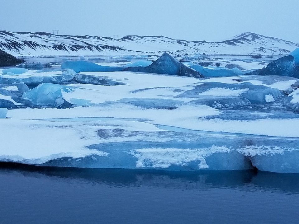 Icebergs dans un paysage gelé avec des terres enneigées en arrière-plan.