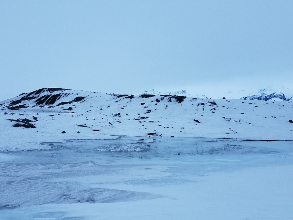 Collines enneigées avec des zones de terre et de glace à découvert.