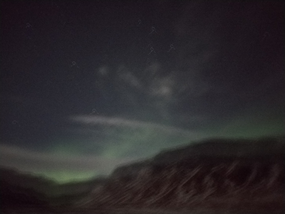 Aurores boréales floues au-dessus d'un paysage enneigé.