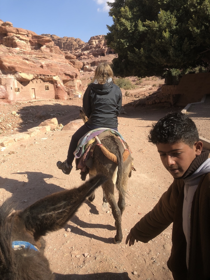 Des gens qui montent un âne dans une région désertique.