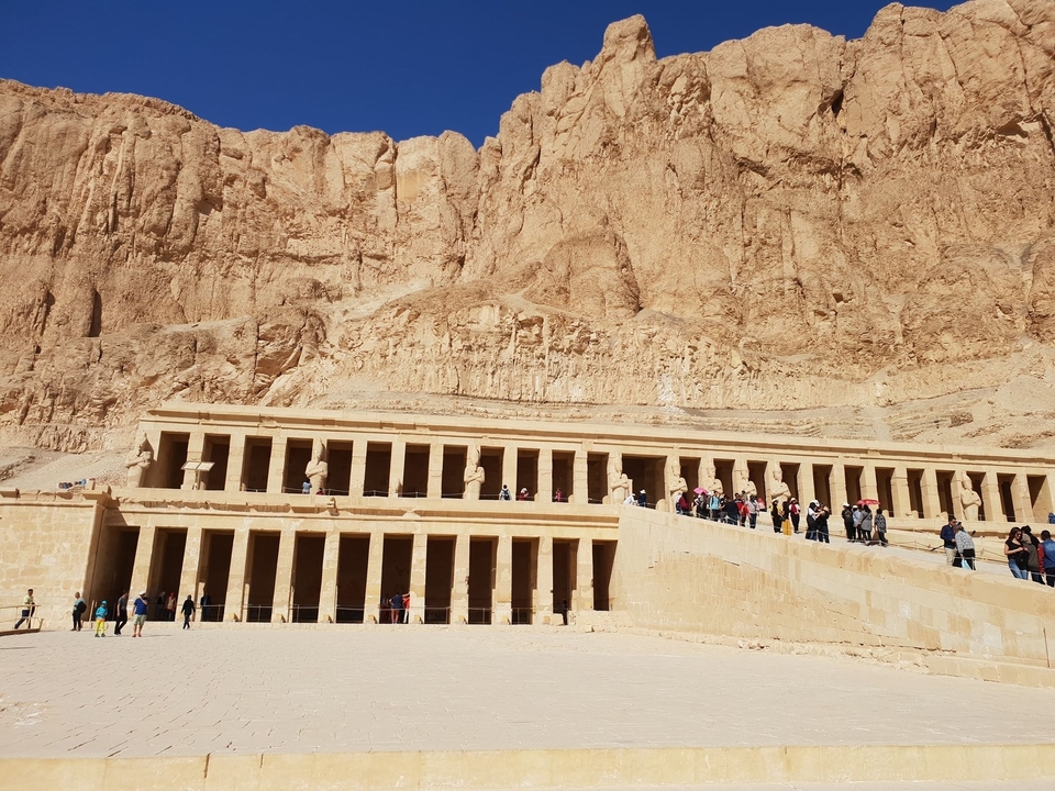 Longue colonnade d'un temple antique avec des visiteurs