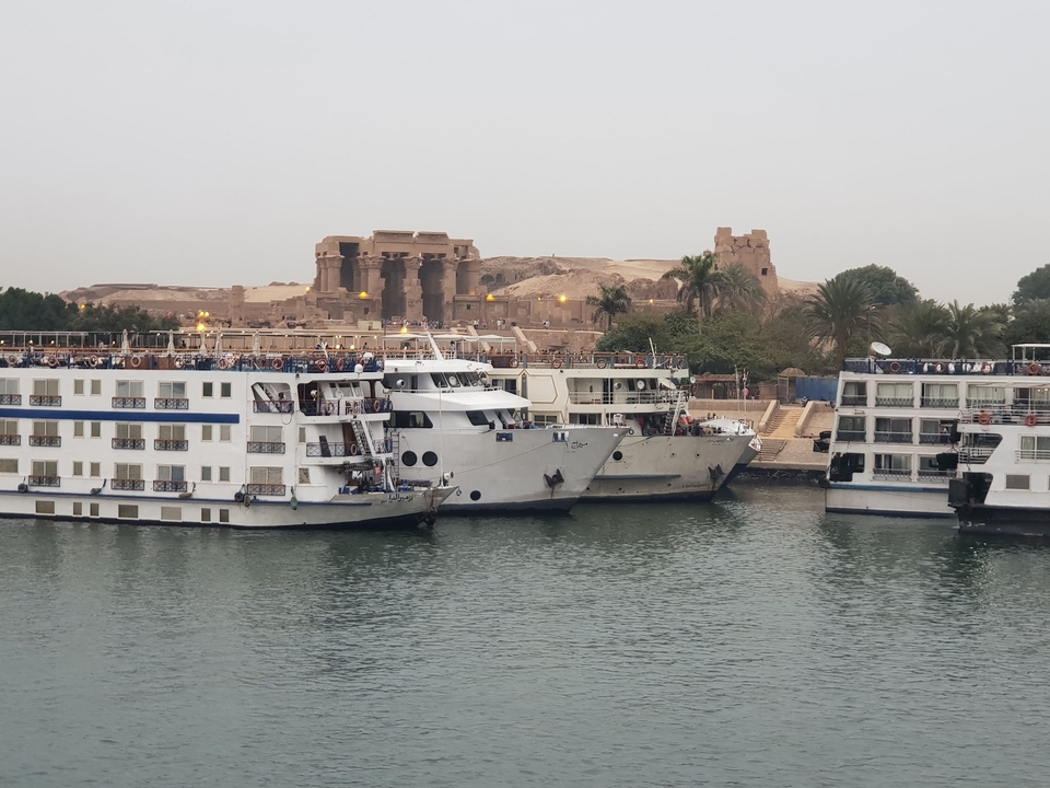 Bateaux de croisière amarrés sur une rivière avec des ruines antiques en arrière-plan