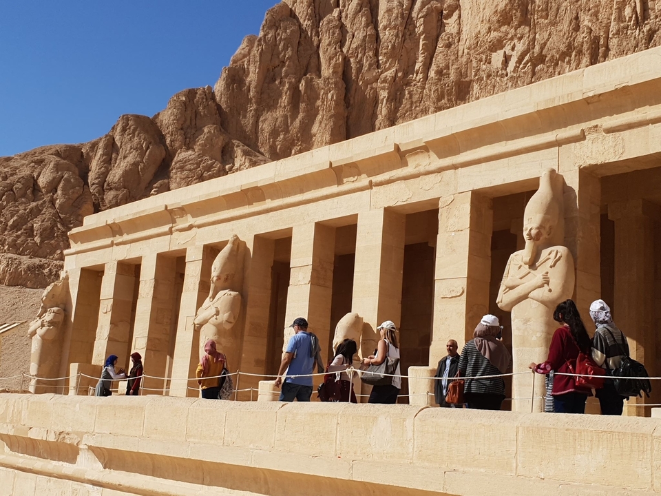 Tourists walking by grand statues and columns
**French translation:**
Des touristes se promenant près de grandes statues et de colonnes
