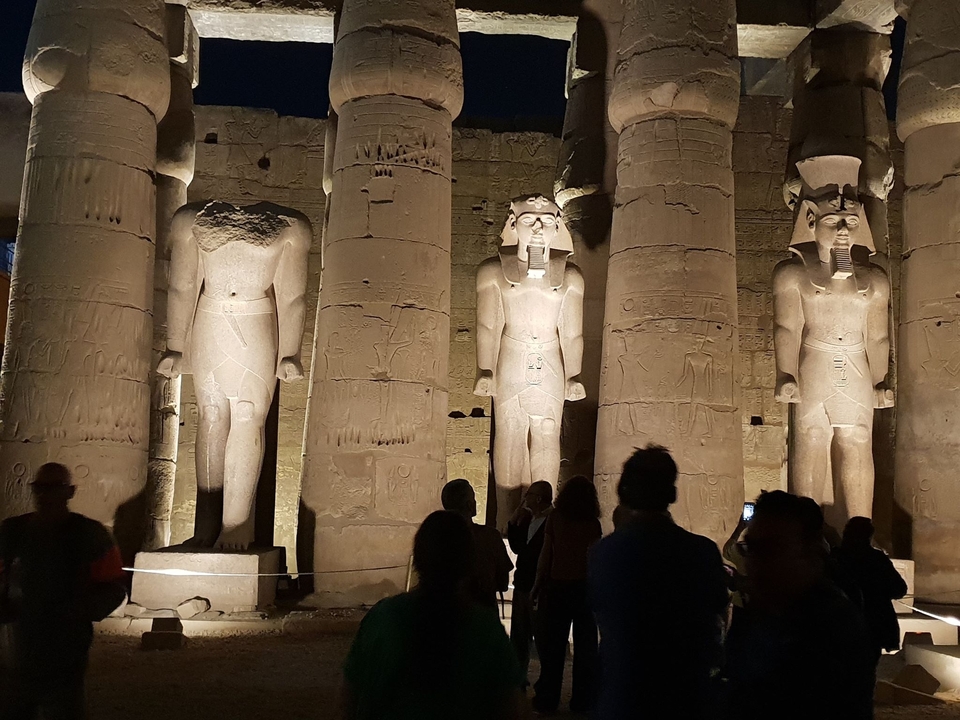 Statues et colonnes d'un temple égyptien éclairées la nuit