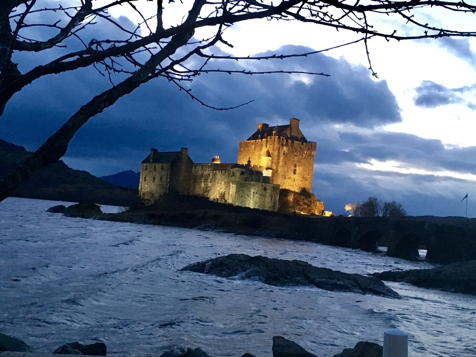 Château illuminé au bord d'un lac le soir.