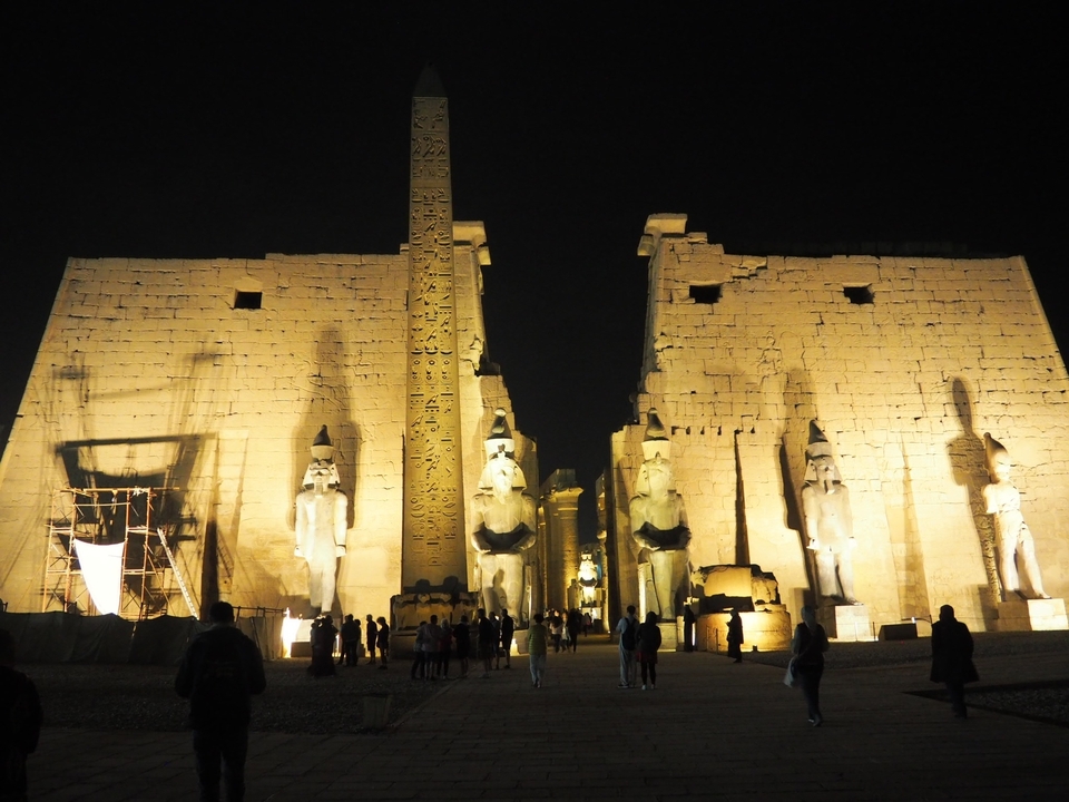 Complexe de temples égyptiens illuminé la nuit.