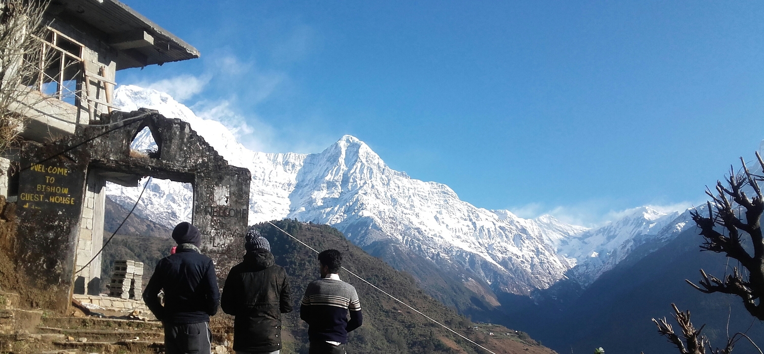 Quatre personnes observant une vue de montagne enneigée depuis un plateau.