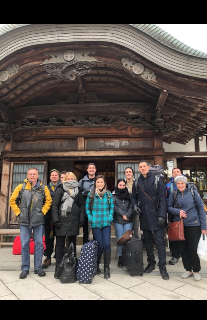 Groupe de personnes posant devant un bâtiment traditionnel.
