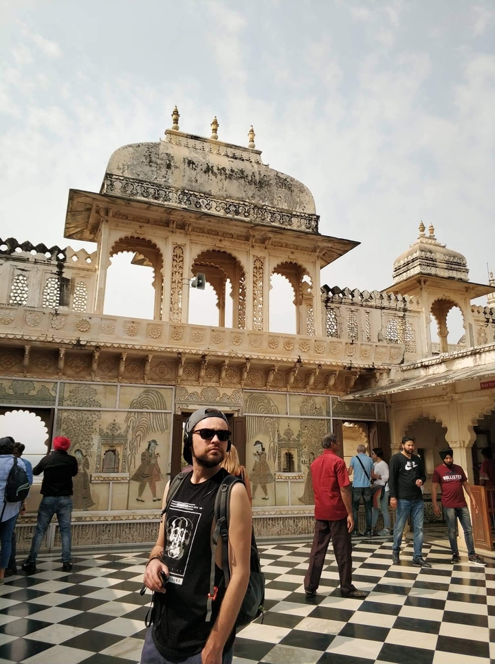 Homme devant une architecture ornementée avec des arches.