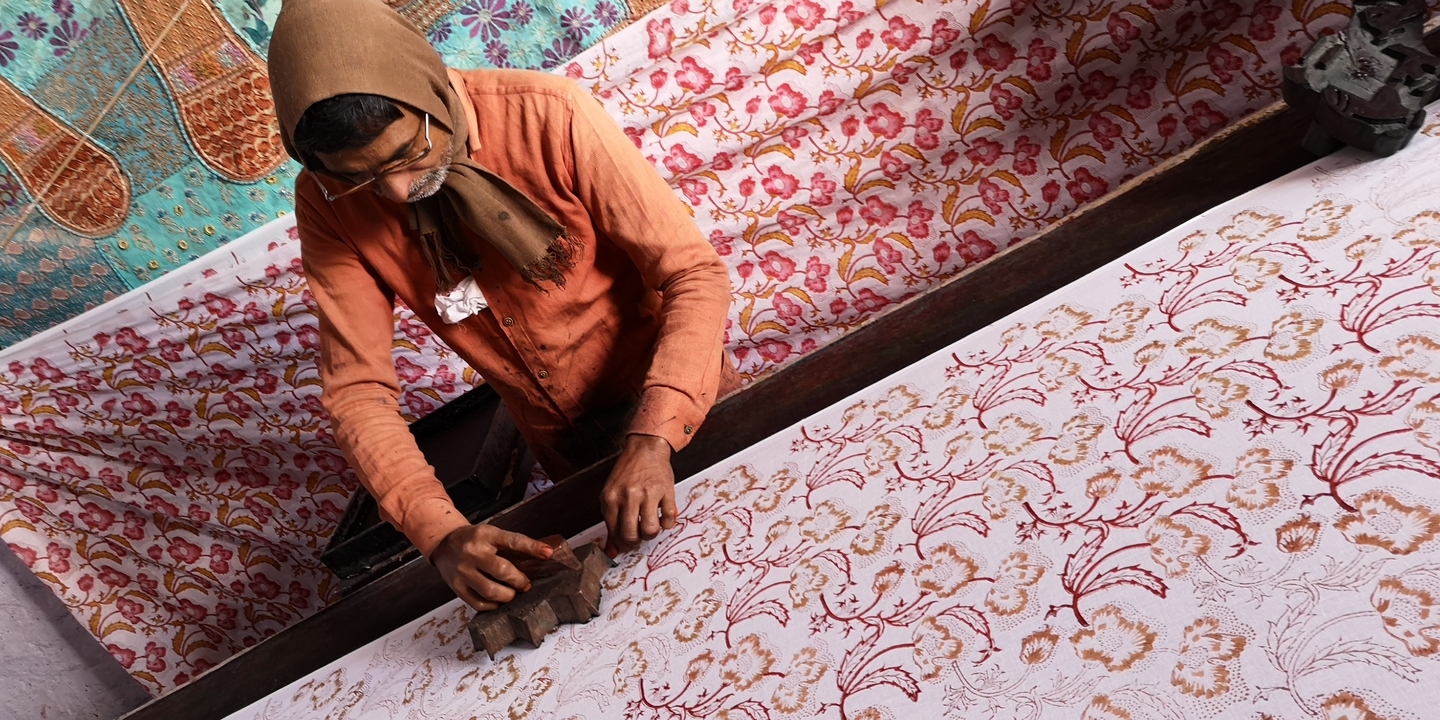Homme engagé dans l'impression à la planche avec des tissus colorés.