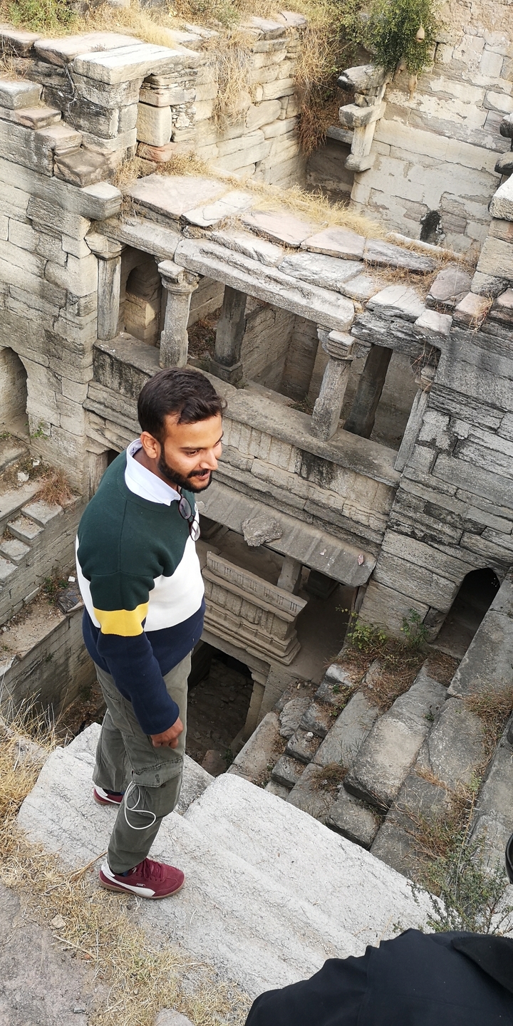 Personne en pull regardant vers le bas dans un cadre de pierre historique.