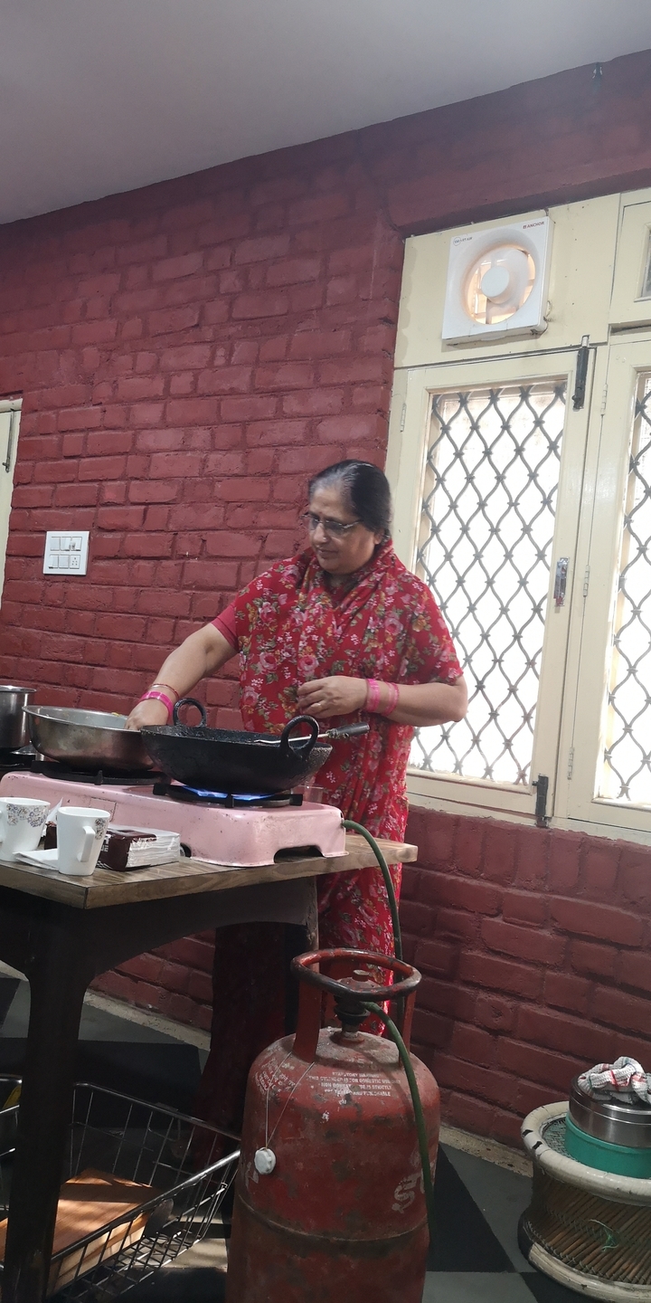 Femme cuisinant dans une cuisine portant une robe fleurie rouge.