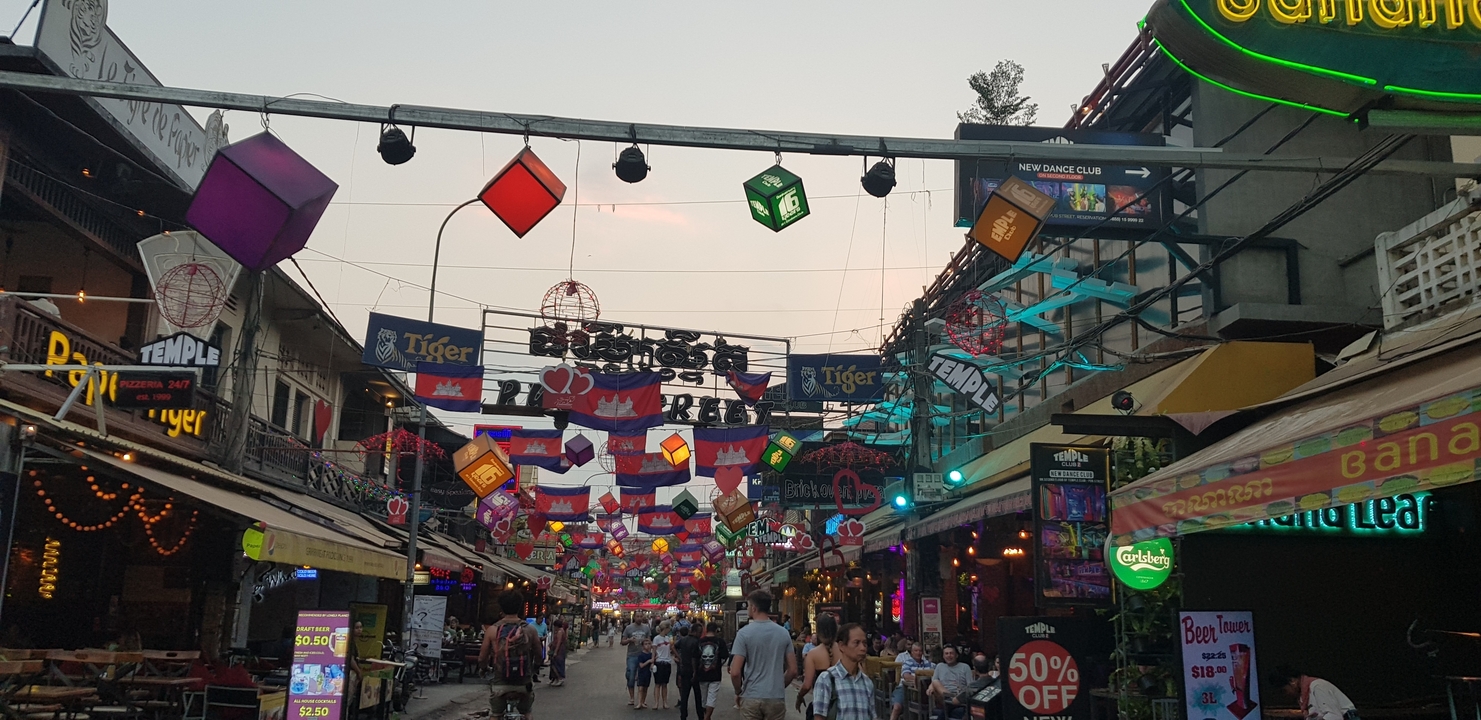 Un marché de nuit animé avec des enseignes colorées et lumineuses et des gens.