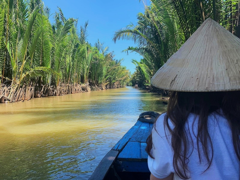 Une personne portant un chapeau sur un bateau faisant une excursion sur une rivière sereine.