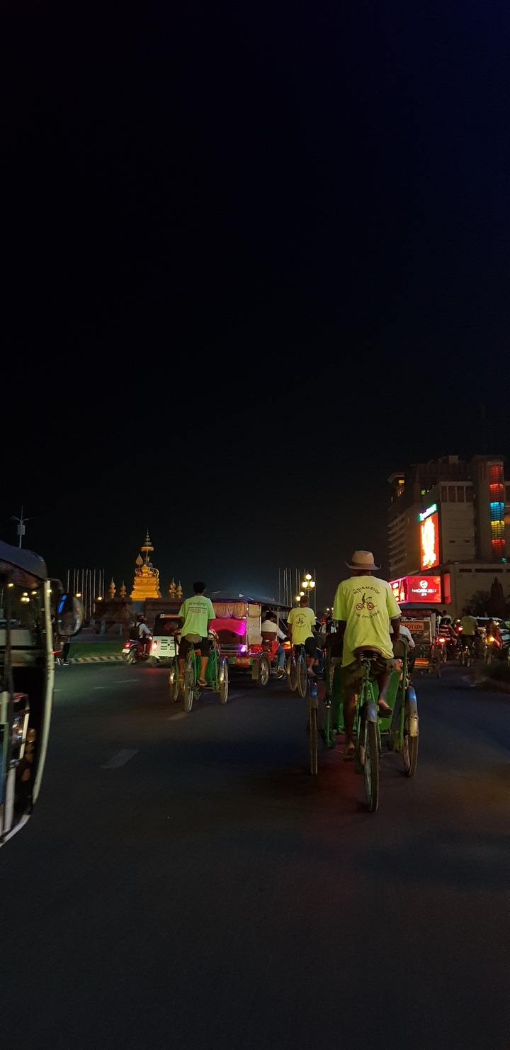 Une rue de ville animée la nuit avec des lumières vives et des gens.