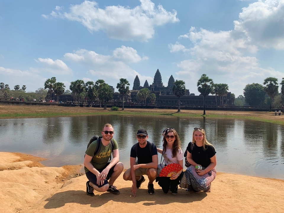 Quatre personnes qui posent devant Angkor Vat avec un lac.