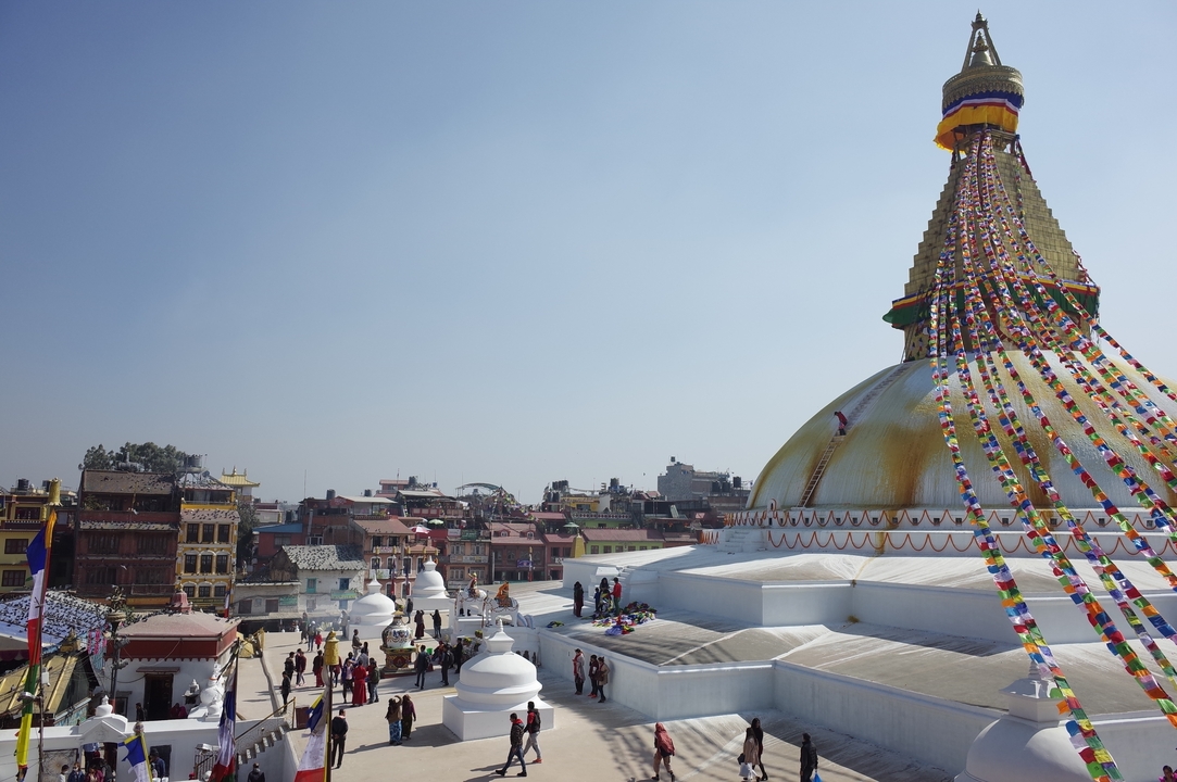 Stupa de Boudhanath à Katmandou avec des visiteurs et des drapeaux de prière.