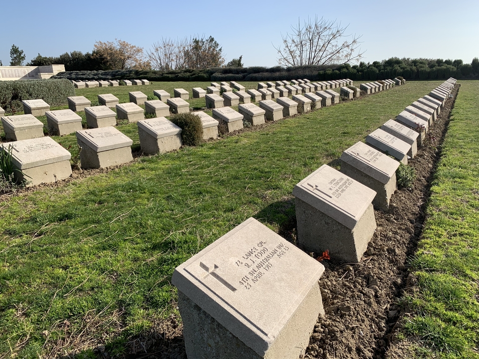 Cimetière militaire avec des rangées de pierres tombales.