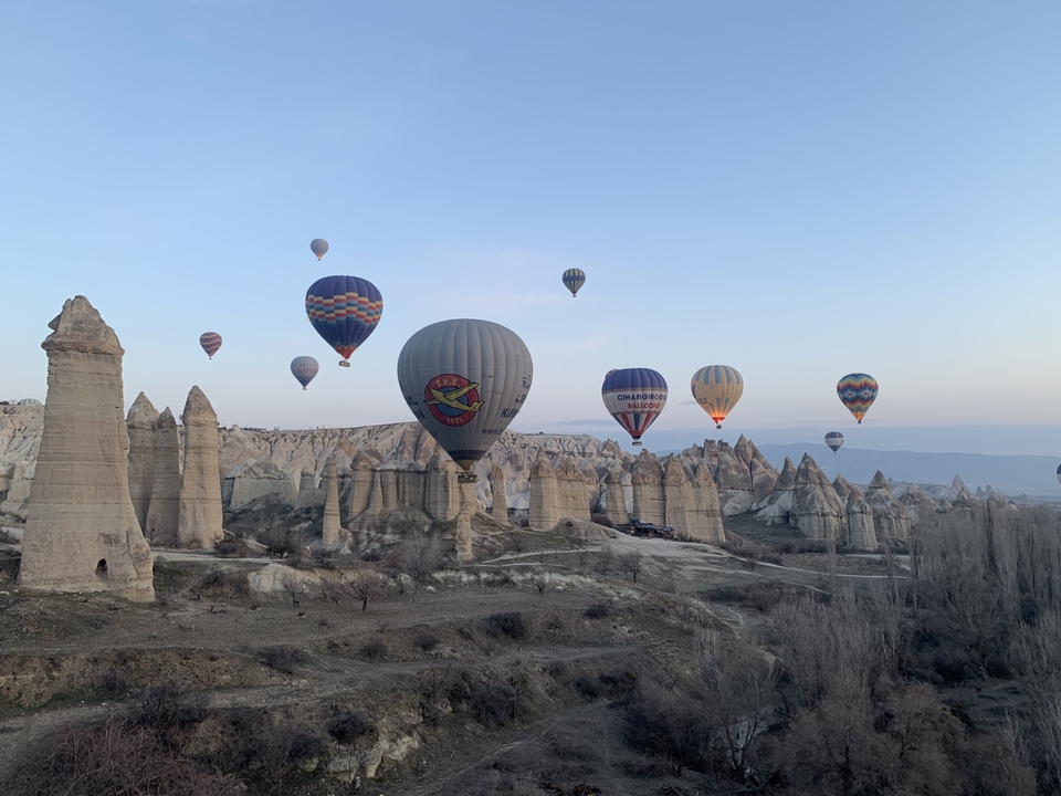 Montgolfières au-dessus de formations rocheuses au lever du soleil.