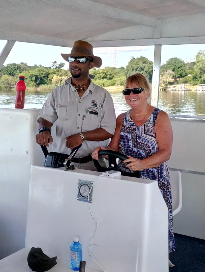 Two people posing on a boat, the woman is smiling.