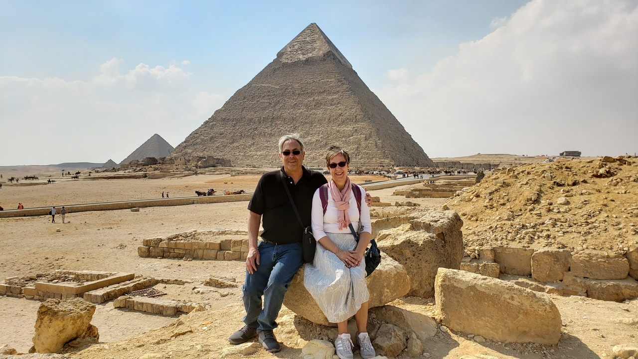Couple assis sur des rochers avec la Grande Pyramide de Gizeh en arrière-plan.