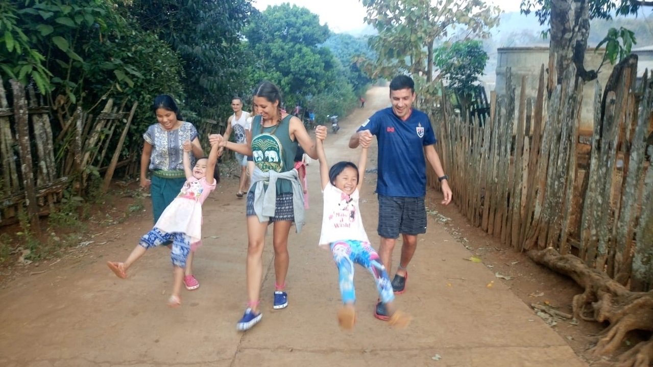 Groupe de personnes marchant et balançant des enfants dans un cadre extérieur.