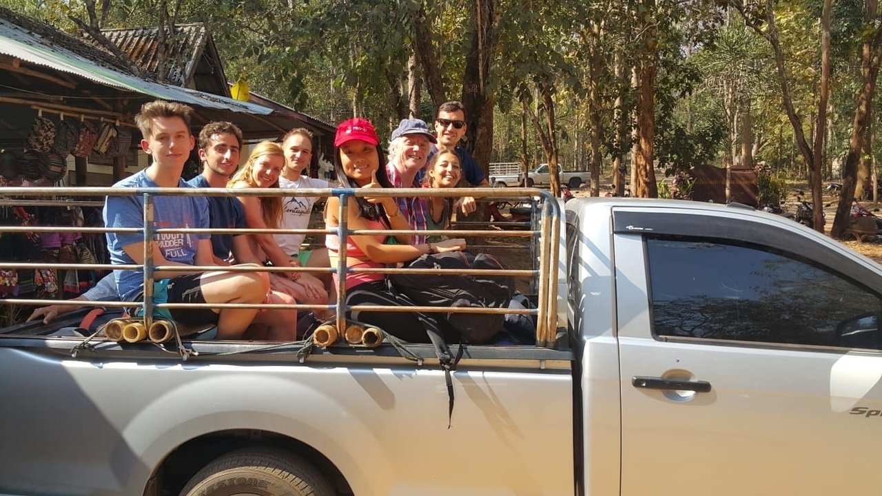 Des personnes assises à l'arrière d'un pick-up à l'extérieur.