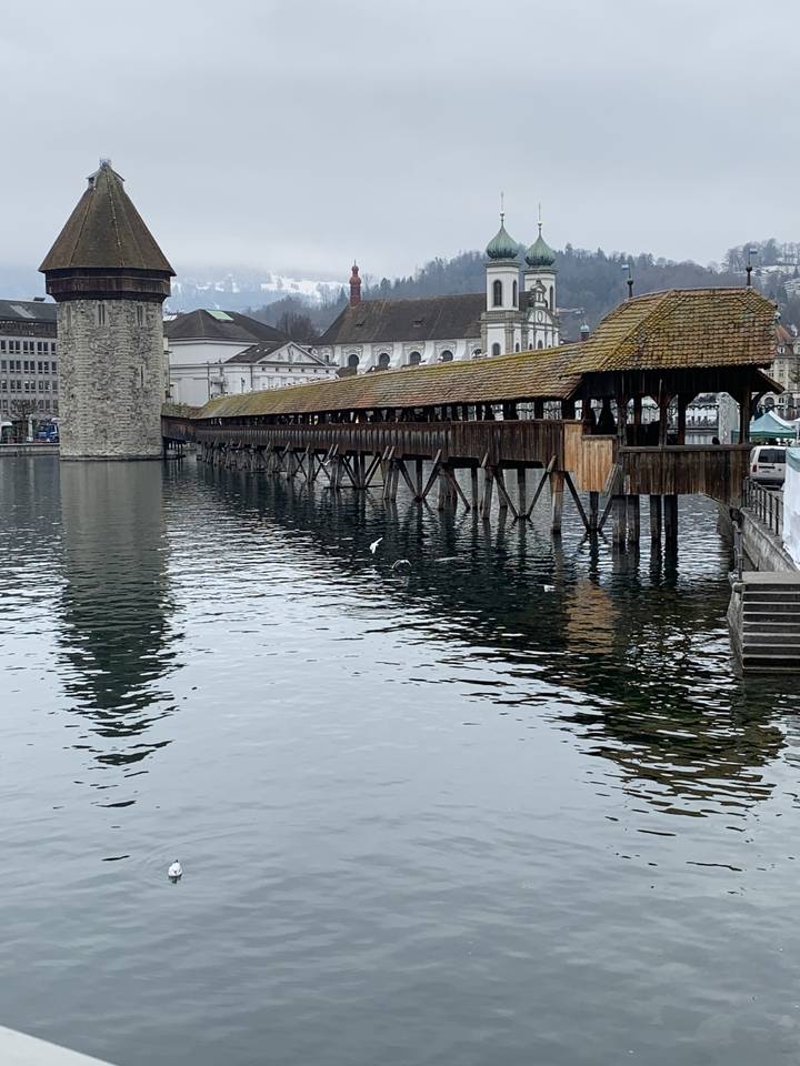 Pont en bois sur l'eau avec une église historique.